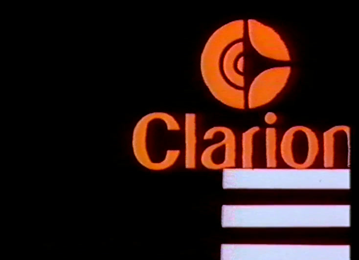 Roundel and wordmark centred over white bars, a pink and a green dot alongside.