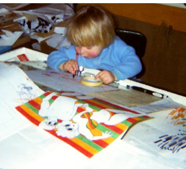 Timo Arnall as a small fair-haired child in a blue jumper, drawing at Marjut’s animation desk among her papers, a striped drawing in the foreground.