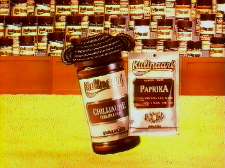 Kaksi maustepurkkia kallistuu eteenpäin samanlaisten purkkirivien yllä keltaisella pohjalla.