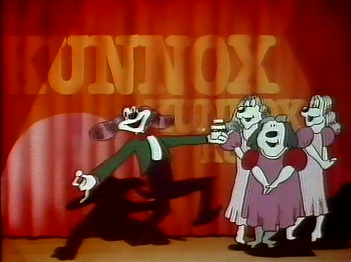 A dog in a green jacket leaps forward while the pink-dressed chorus sings behind.