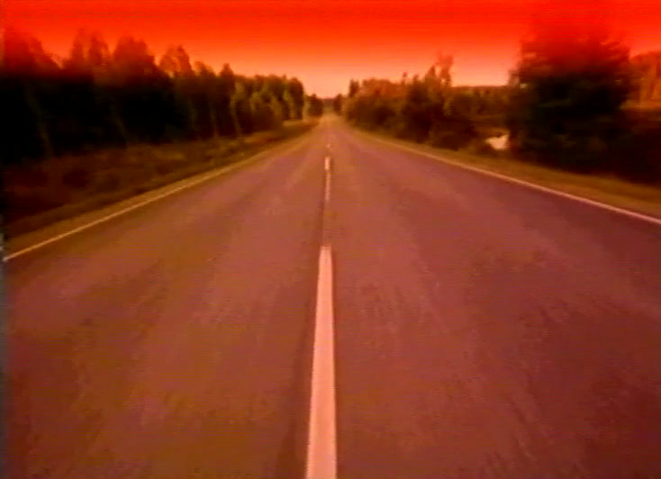 Sama tie kesällä iltahämärässä, punainen taivas palaa edessä olevien puiden yllä.