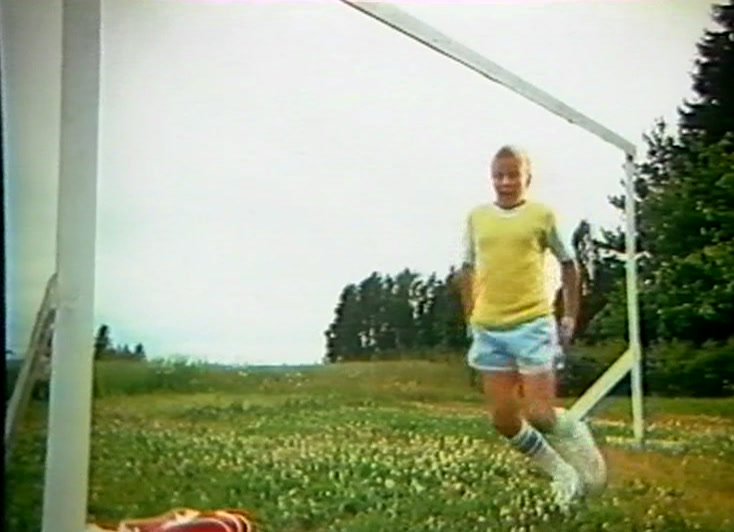 Matalalta kuvattua juoksua korkeassa heinässä ja päivänkakkaroissa sinisen taivaan alla.