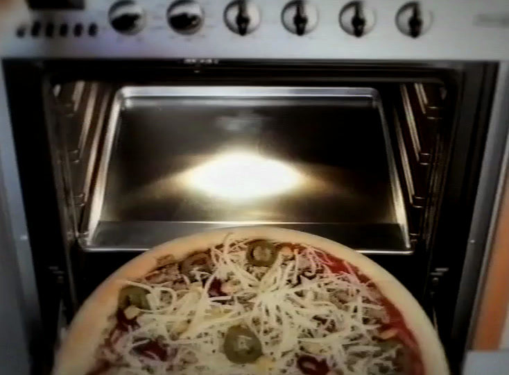 Täytetty pizza liukuu valaistuun kotiuuniin, luukun yläpuolella rivi säätimiä