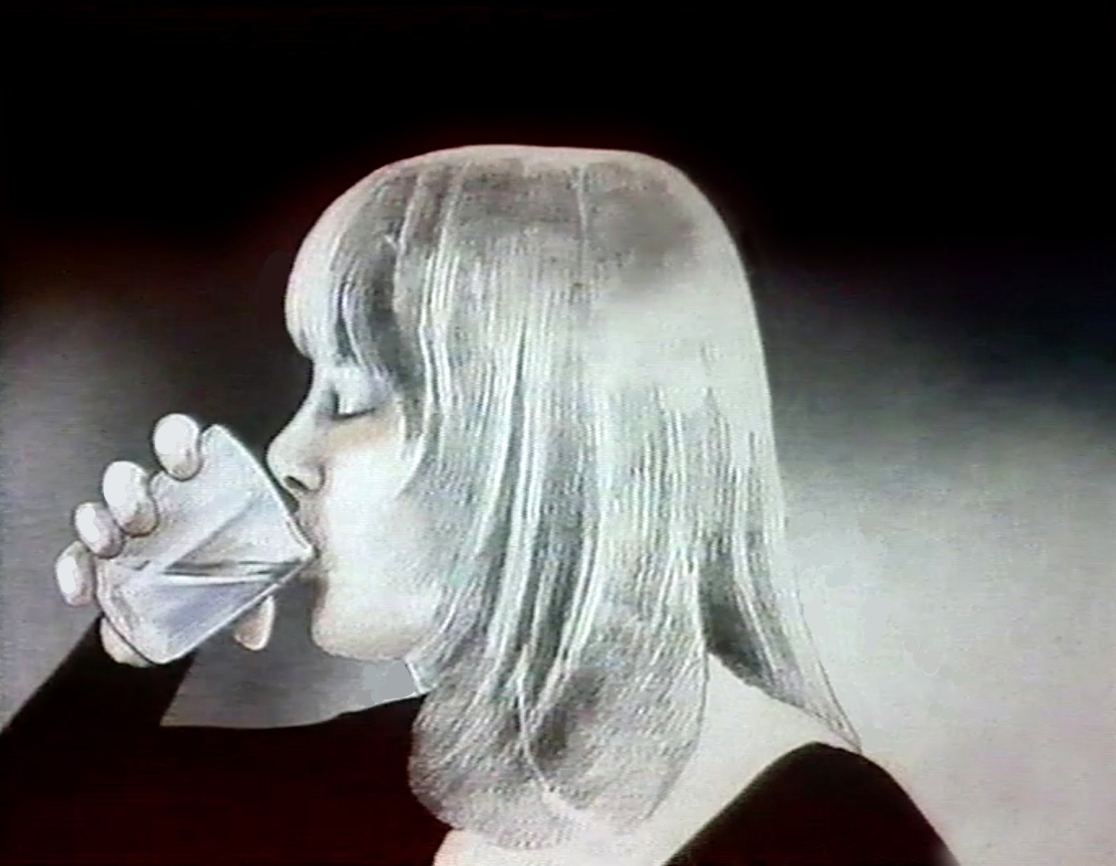 Still from Treo, a fair-haired woman in profile drinks from a faceted glass with her eyes closed