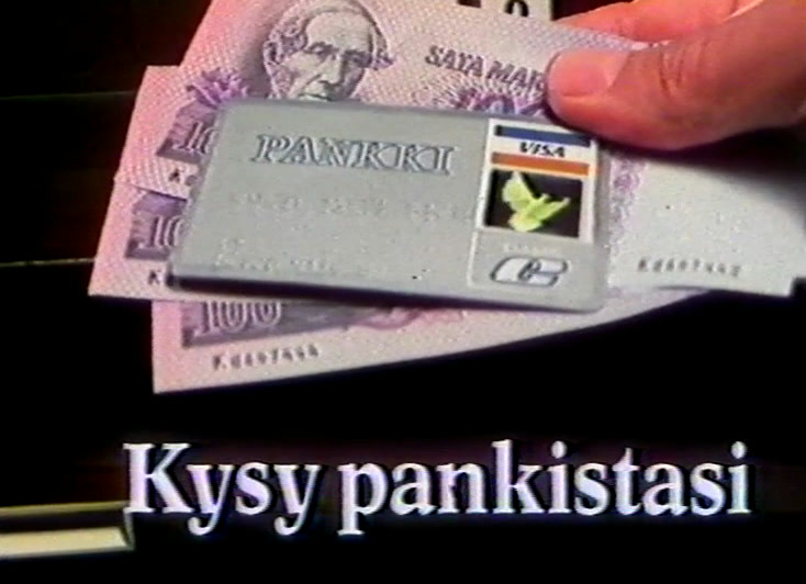 Käsi liu'uttaa maksukortin kahden setelin päälle, alla valkoinen teksti mustalla.