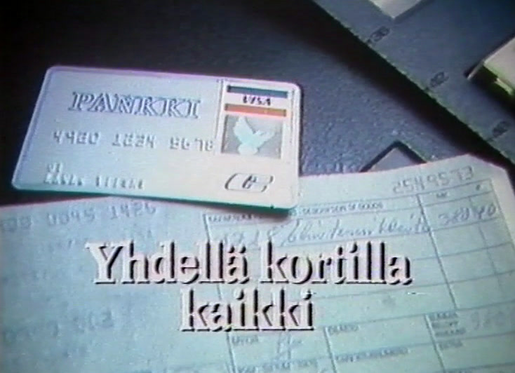 Pankkikortti painettujen kuittien päällä, alareunassa teksti.