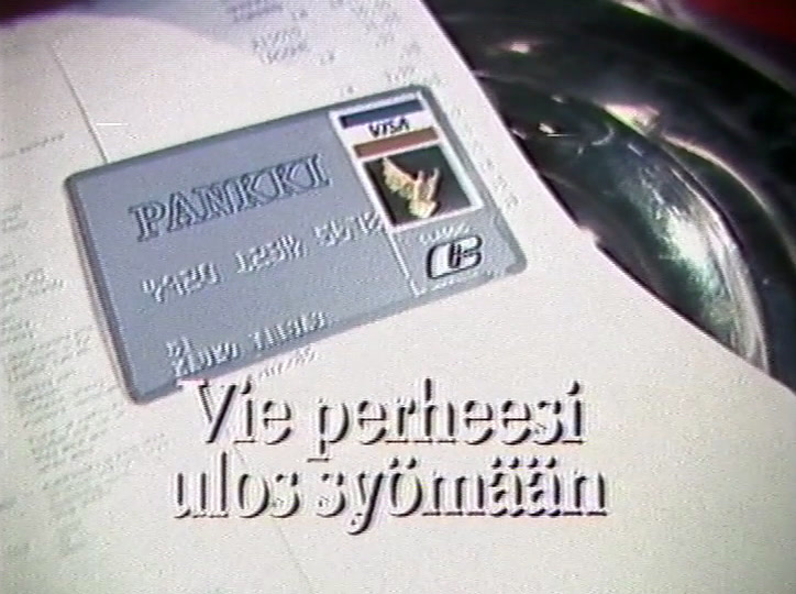 Visa-kortti painetun laskun päällä hopeisen vadin vieressä, alla lopputeksti.